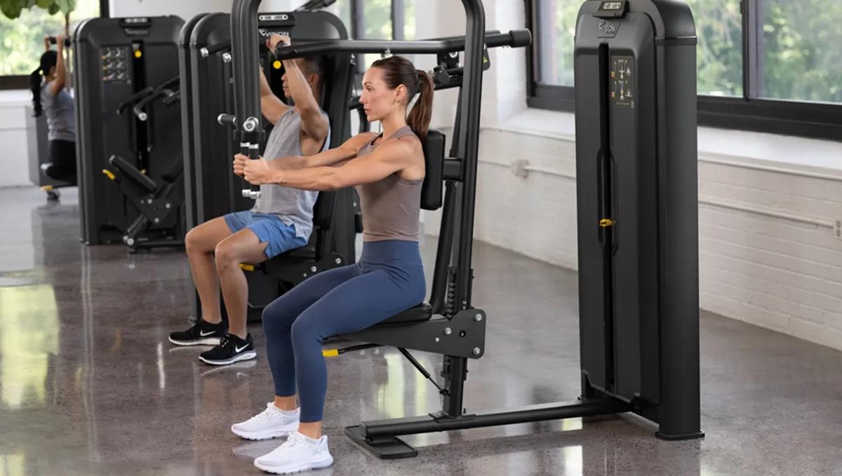 People using a Matte Black Vision Fitness selectorized strength equipment in a gym.