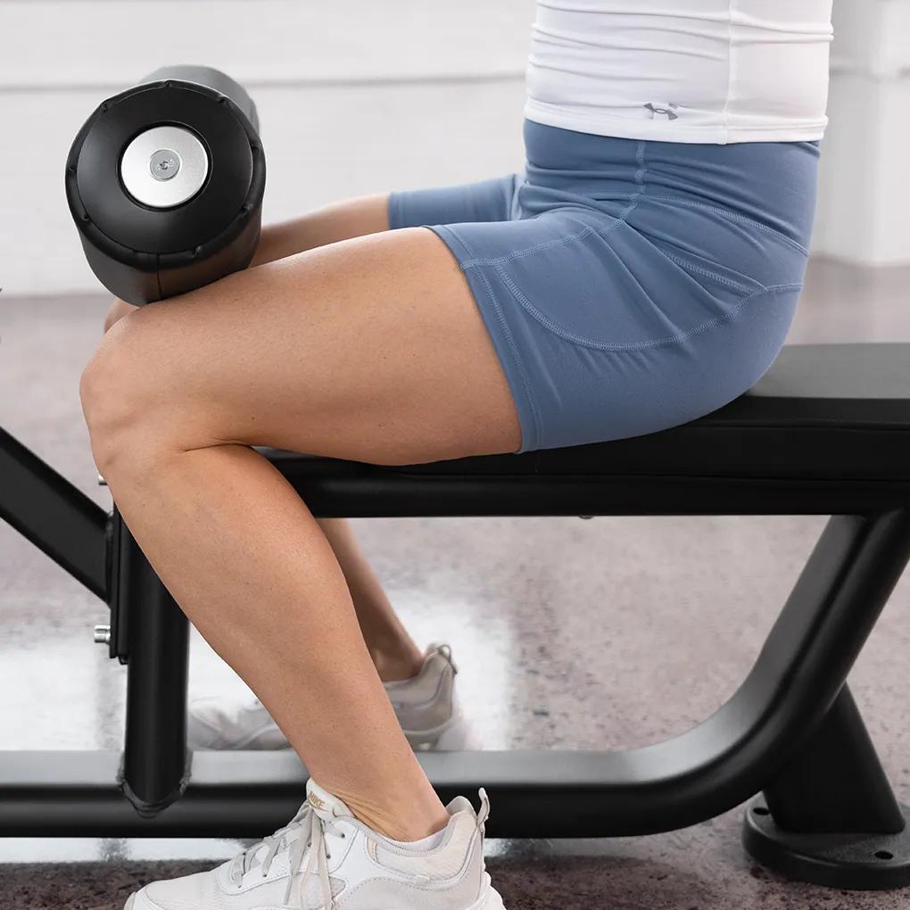 Close-up of a person seated on the Keystone Lat Pulldown / Seated Row machine with thighs secured under the padded support.