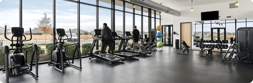 Two people walking on treadmills in front of floor to ceiling windows