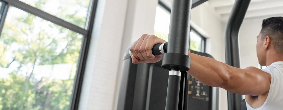 Close-up of a person gripping the handles of the Vision Fitness Pec Fly/Rear Delt machine, showing arm positioning and start posture for the rear delt fly exercise.