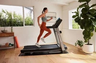 A person in dark orange leggings running on a Schwinn Treadmill at home