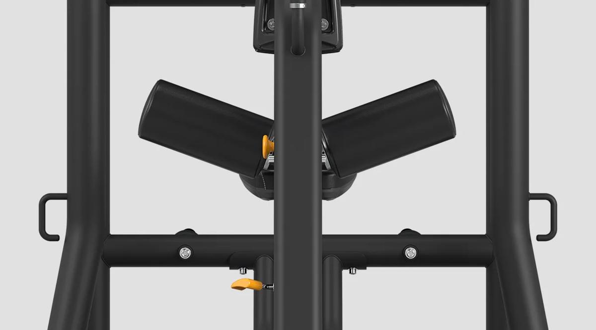 Rear view of angled thigh pads with a yellow adjustment knob on a Matrix Fitness machine in Matte Black, flanked by two vertical frame handles.