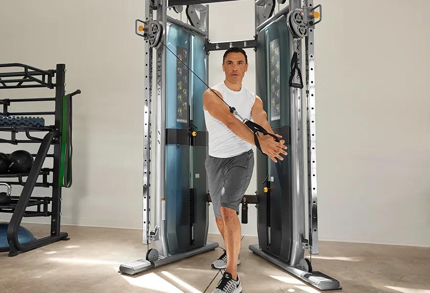 Man pulling down cable while using Matrix Fitness functional trainer