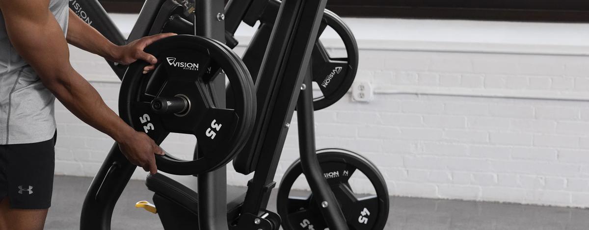 A close-up view of a person loading some weight plates to the side horn on the Vision Vertical Chest Press.