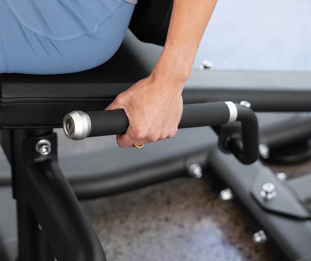 A person's left hand on the rubber handles on the side of the Vision Leg Extension.