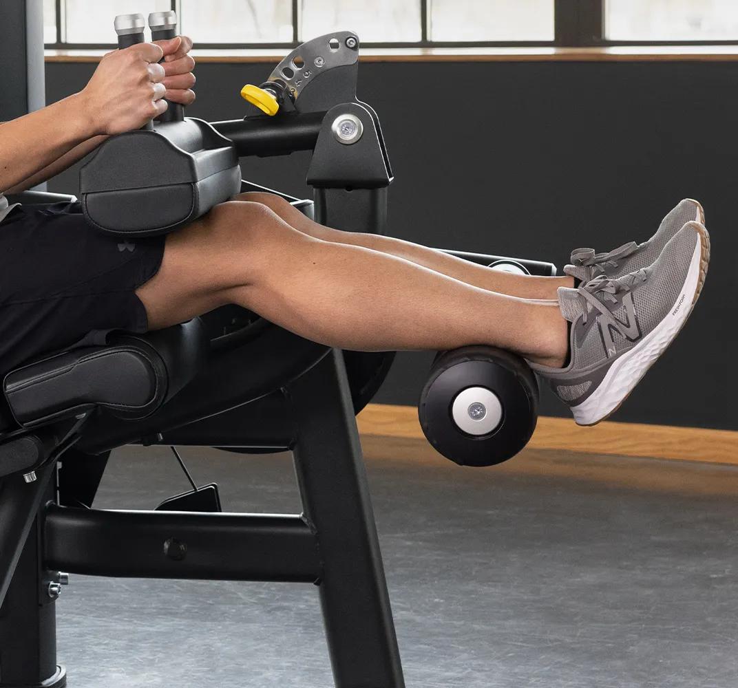 Close-up of a person using the Keystone Seated Leg Curl, highlighting the padded ankle roller.